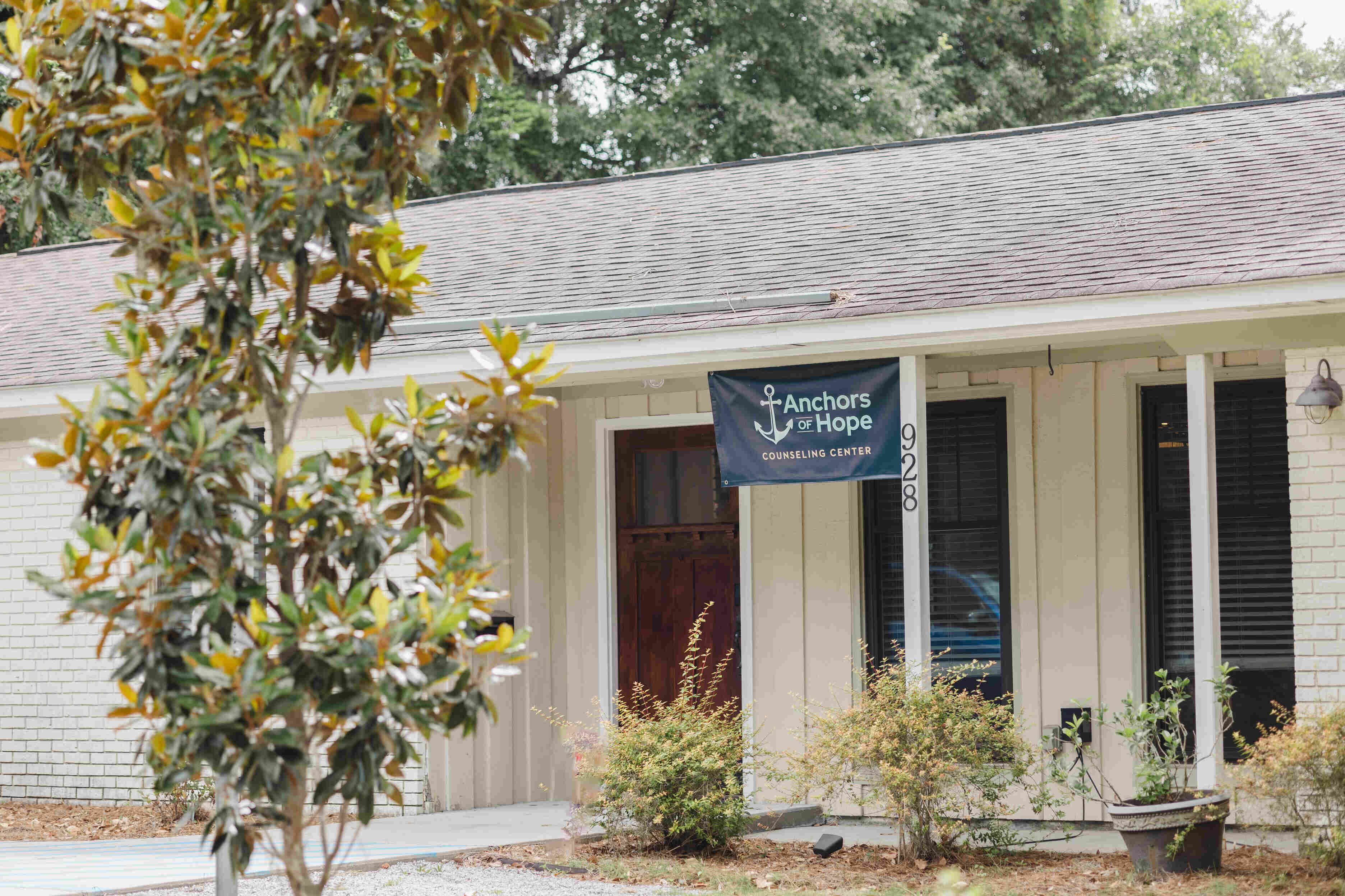 Anchors of Hope Counseling Center's office sign with the West Ashley office building in the background.